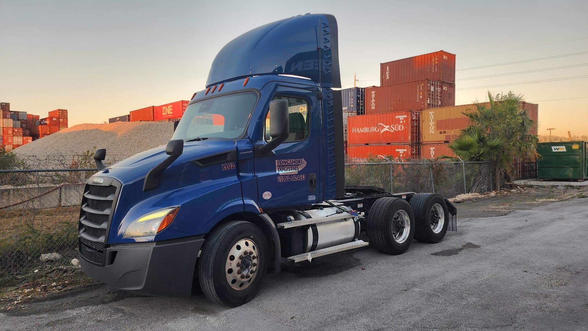 Longshore Logistics blue truck parked in a container yard
