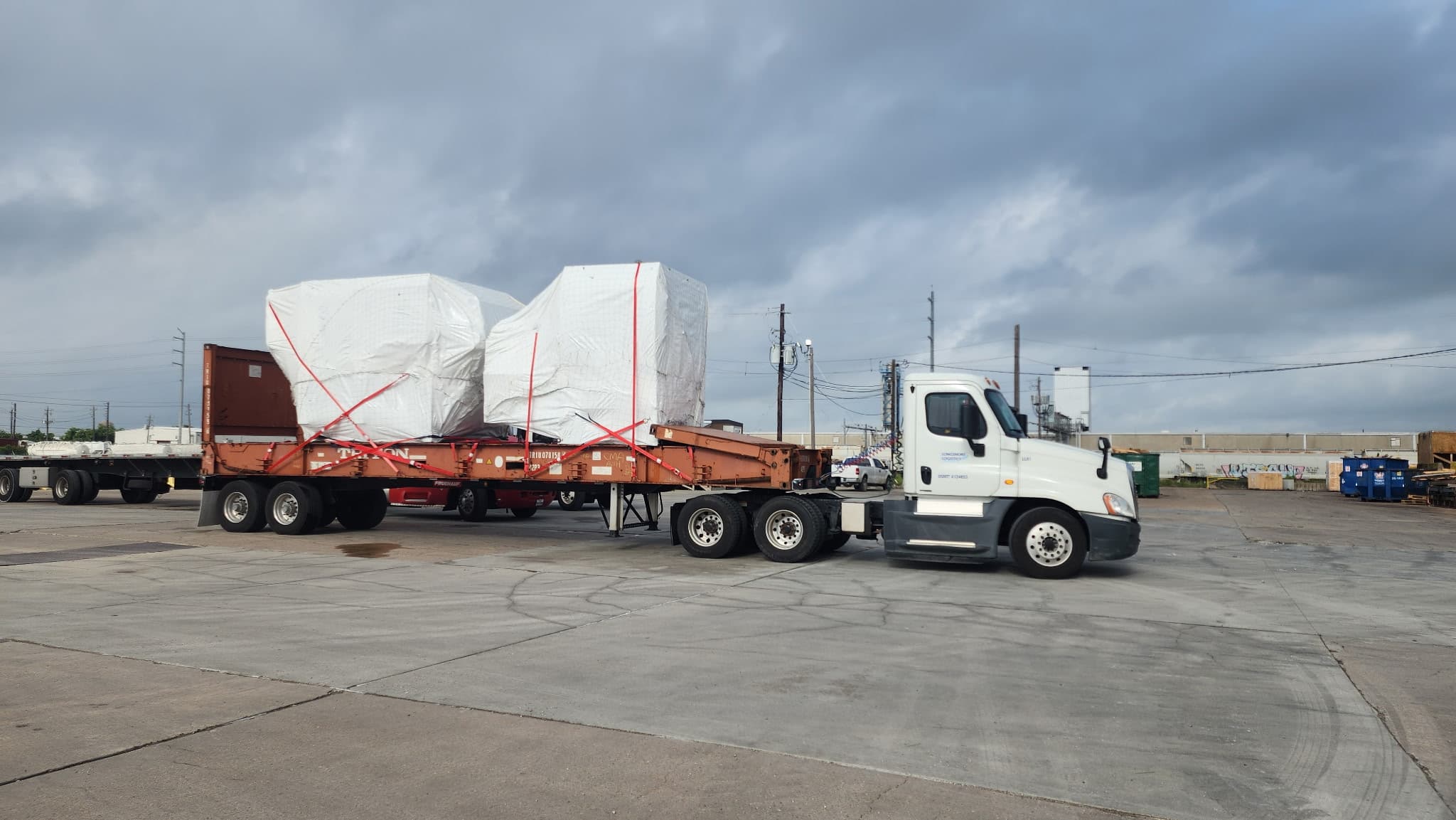 Longshore Logistics white truck hauling a wrapped industrial load