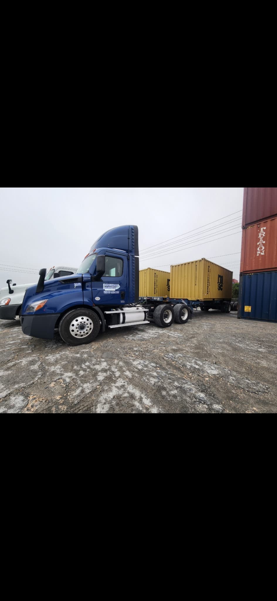 Longshore Logistics blue truck hauling a yellow shipping container