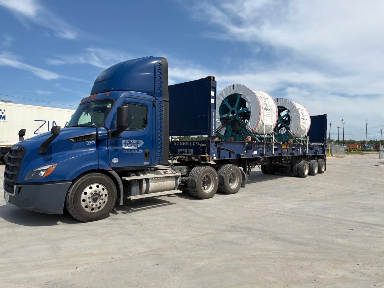 Longshore Logistics blue truck hauling large industrial reels