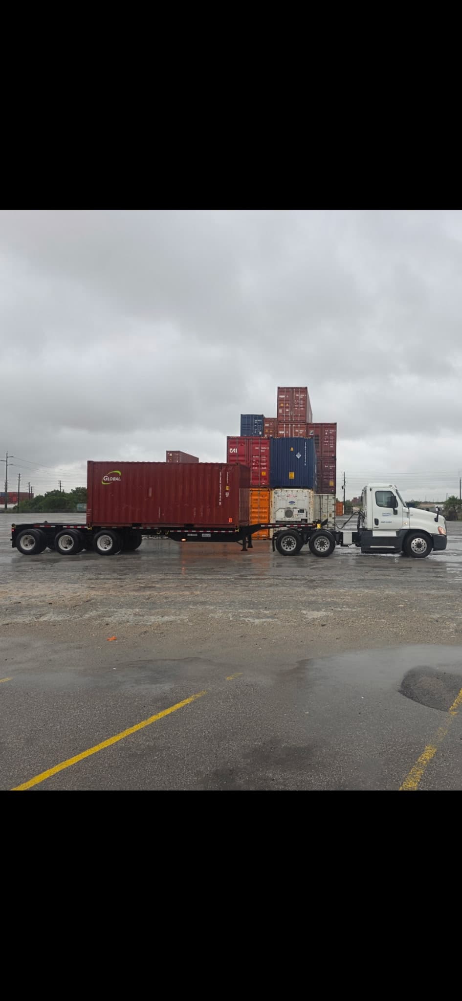 Longshore Logistics white truck hauling a red shipping container in a Texas container yard